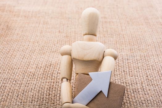 Wooden man holding a paper arrow on canvas