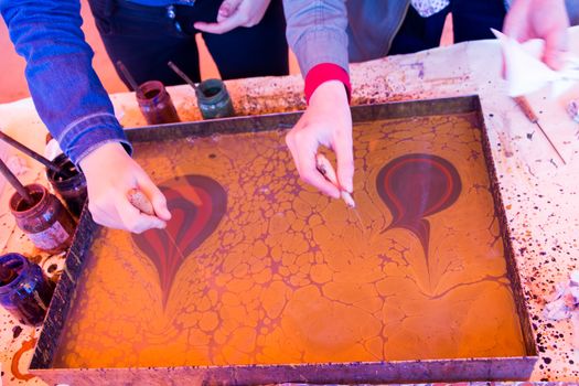 Hand drawing with stick stained inks on water surface