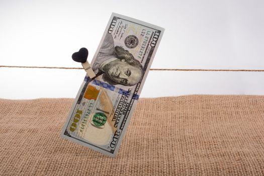 American 100 dollar banknotes with a heart clip on a string