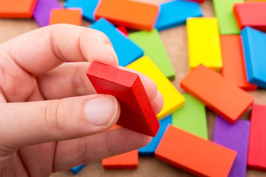 Hand holding one of the wooden blocks of various colors