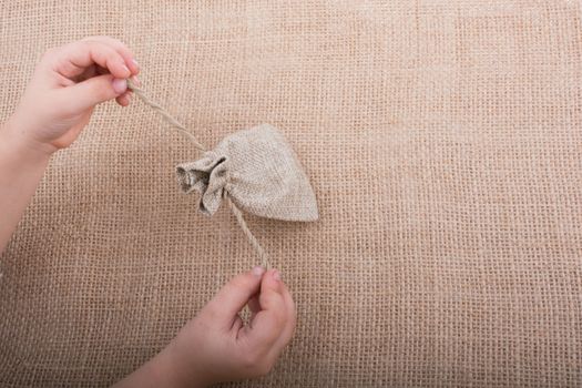 Hand holding an empty little sack made of linen