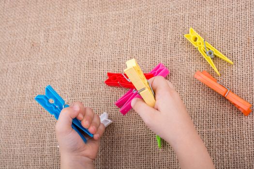 Color clothespin in hand on a linen canvas background