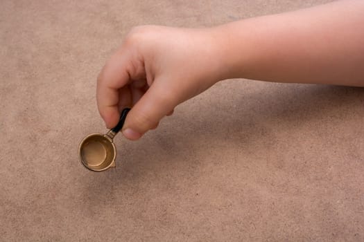 Hand holding a little model pan as a kitchen utensil