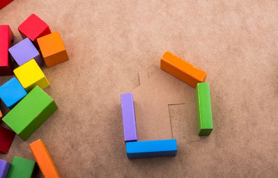 House shape formed out of building blocks on a brown background