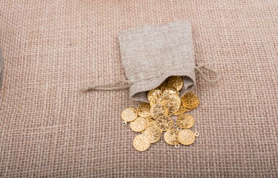 Fake gold coins out of a little sack on canvas