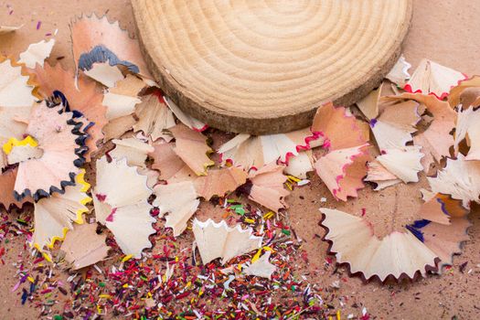 Colorful pencil shavings and a piece of wood