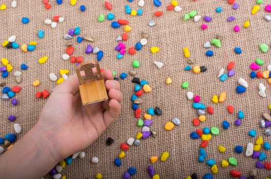 Little chair in hand amid colorful pebbles on canvas