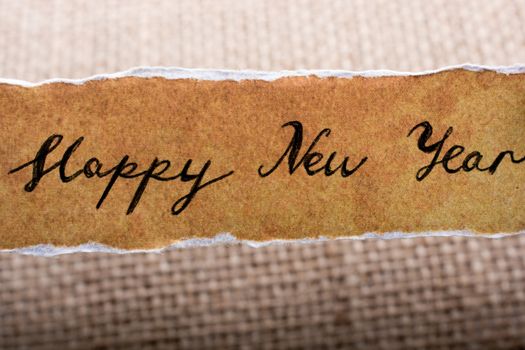 Happy new year written on a torn yellow paper on canvas