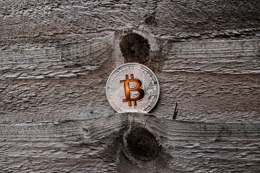 Digital currency physical silver bitcoin coin with orange sign on the wooden background.