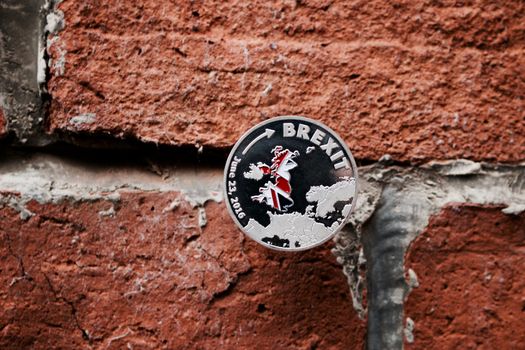 Europe leaving. Silver brexit coin with british map on the brick wall.
