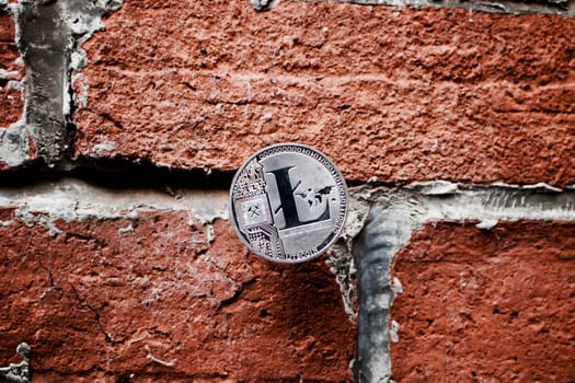 Cryptocurrency physical silver Litecoin coin on the brown brick wall.