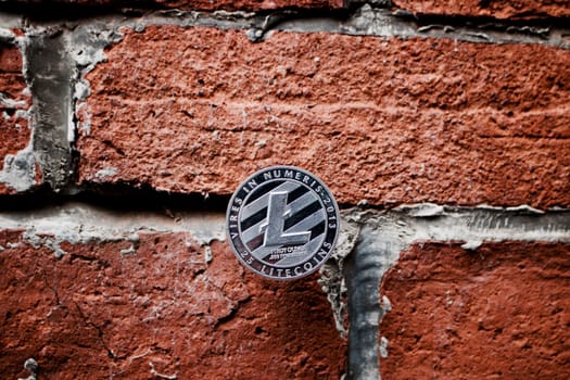 Digital currency physical silver litecoin coin on the brick wall.