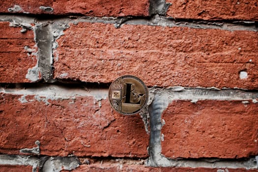 Digital currency physical gold litecoin coin on the brick wall.