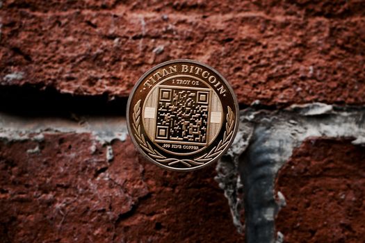 Cryptocurrency physical gold titan bitcoin coin on the brick wall.