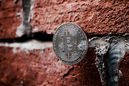 Digital currency physical silver bitcoin coin on the brick wall.