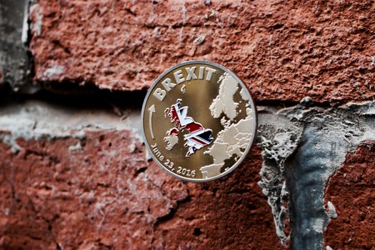 Europe leaving. Gold brexit coin on the brick wall with british map. June 23.