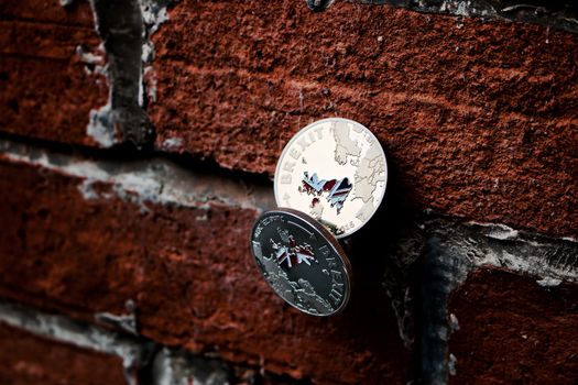Two, silver and gold brexit coins on brick wall. British flag. Europe leaving.