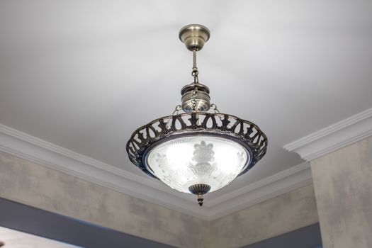 Huge chandelier closeup with electric bulbs on fancy ceiling