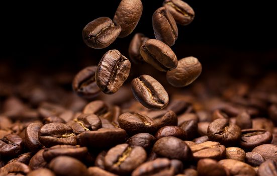 Falling coffee beans. Dark background with copy space, close-up