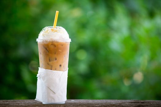 iced coffee with whipped cream in plastic cup on the garden table