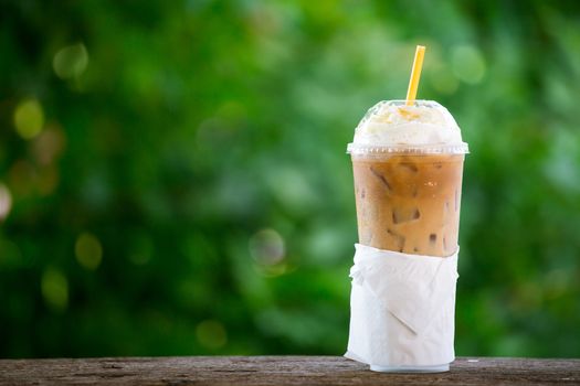 iced coffee with whipped cream in plastic cup on the garden table