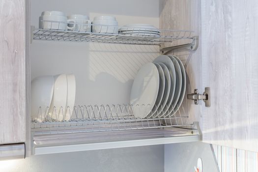 plates are dried on a shelf for dishes in the kitchen cabinet