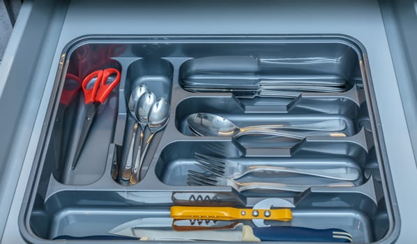 Grey silverware drawer with forks spoons and other  kitchenware