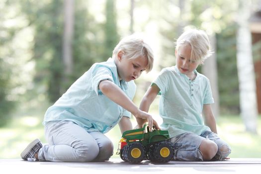 Little brothers playing with toy cars outdoors