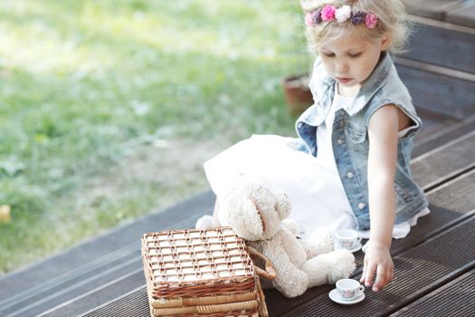 Pretty girl playing with teddy bear outdoors