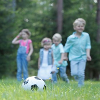 Happy children playing football in summer park