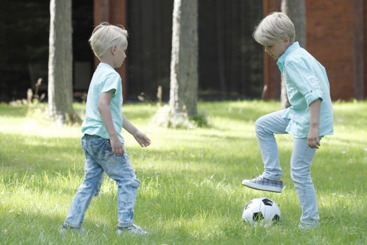 Happy children playing football in summer park