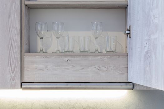 Transparent clean glasses on shelve in open cabinet