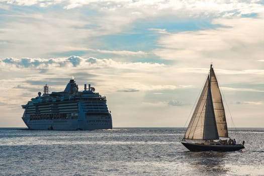 Blue sailboat traveling against the cruise liner in Riga