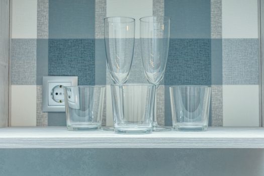 Transparent clean glasses on shelve in open cabinet