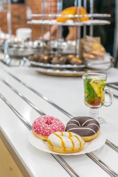 Three donuts on restaurant table with cup of delicious tea