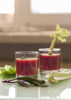 still life with tomato juice in glass glasses with greens