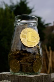 Digital currency physical gold litecoin coin on glass jar with money.
