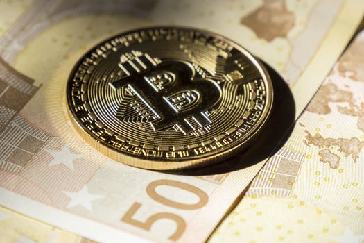 Cryptocurrency coins over euro banknotes; Bitcoin  coins