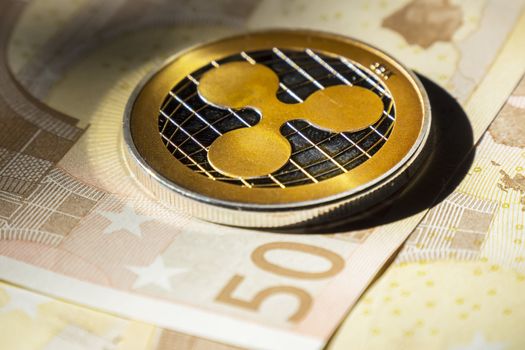 Cryptocurrency coins over euro banknotes; Ripple coin