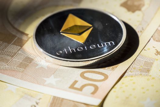 Cryptocurrency coins over euro banknotes; Ethereum coin