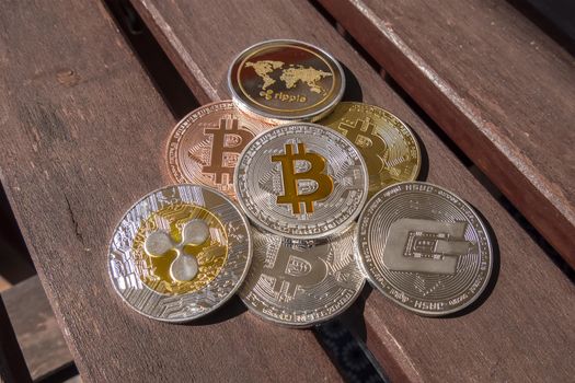 Cryptocurrency coins over a wood table; Bitcoin, Ripple, Dash