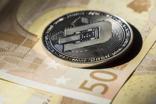 Cryptocurrency coins over euro banknotes; Dash coin