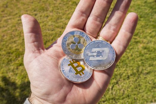 Cryptocurrency coins in a hand; Bitcoin, Ripple, Dash