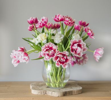 vase with red pink and white tulips on wooden plate 
