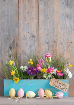 Spring flowers in a wooden pot with row of easter egg
