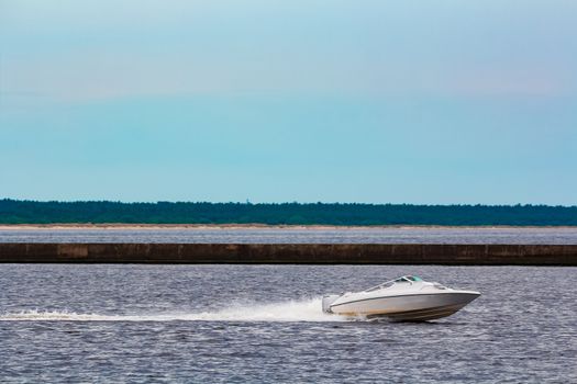 White speed boat moving fast to the Baltic sea. Water sport