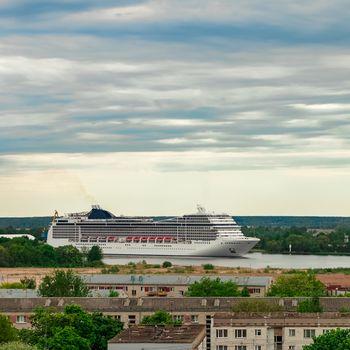 Big white cruise liner sailing past the cargo port