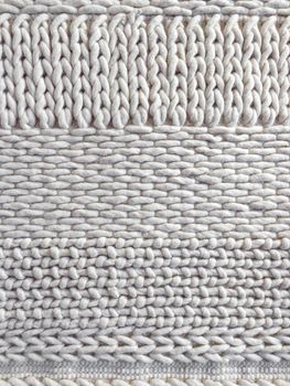 White wool knitted background with simple ornament. Handcrafted material.