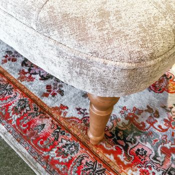 Detail of a luxurious armchair with wooden legs on a classic rug.