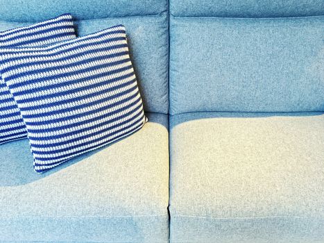 Striped cushions on a blue textile sofa. Contemporary furniture.